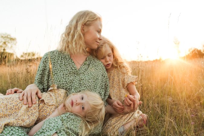 Calm mother embracing daughters in sunlight