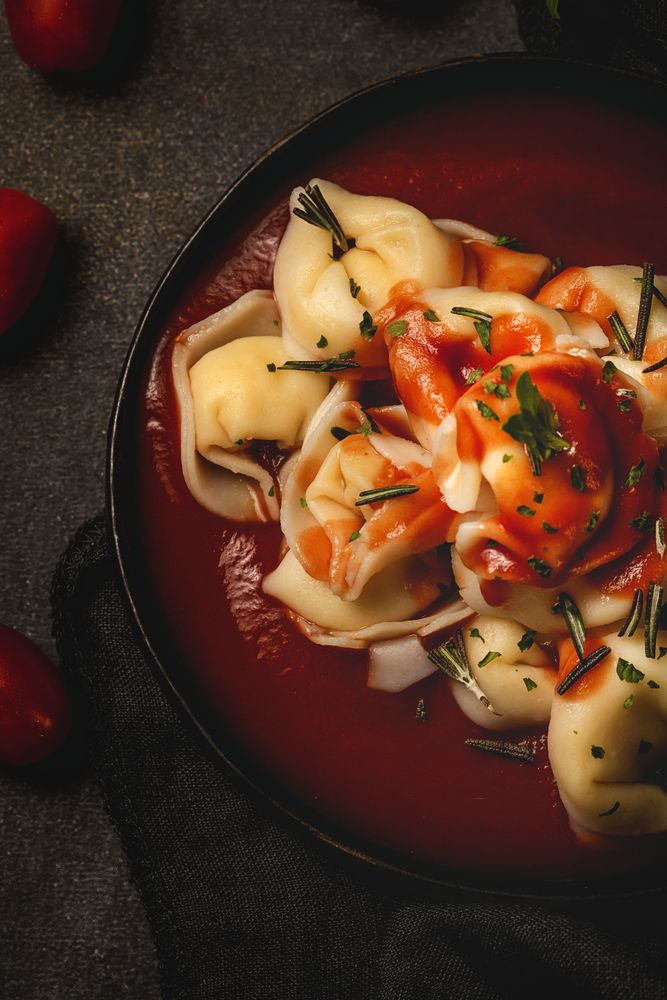 Plate of delicious ravioli with tomato sauce served on table