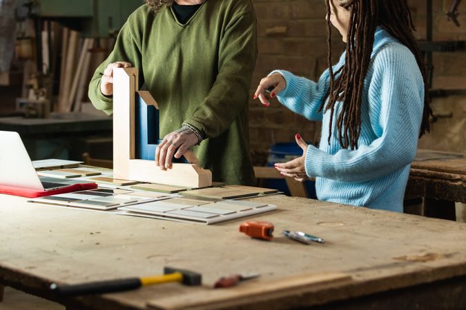 Carpenter making wooden frame while talking to client