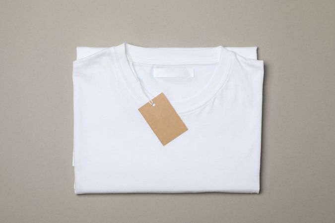 Folded blank plain t-shirt with tag on gray background, space for text
