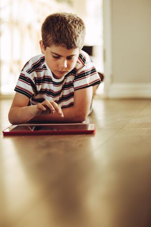 Boy sitting on floor at home using a tablet pc