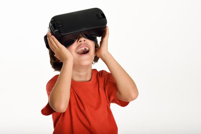Smiling girl in VR glasses and gesturing with hands on goggles