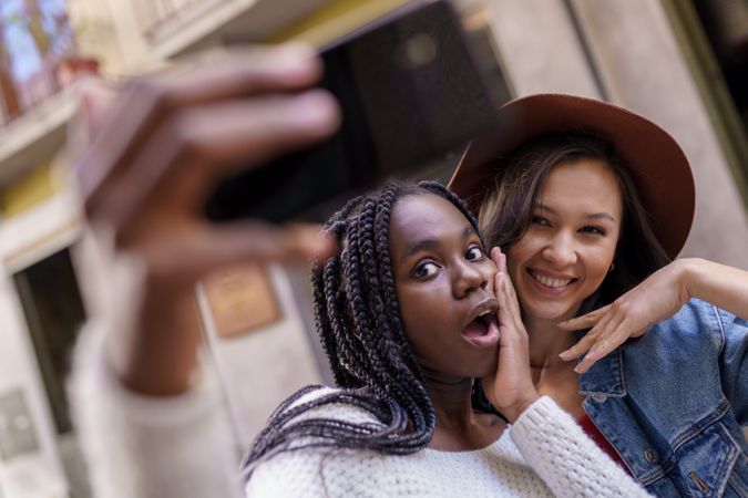 Female friends looking surprised at smart phone taking a selfie