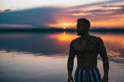 Sensual man against sunset sky on beach