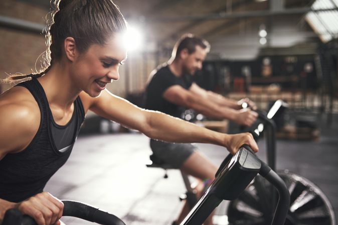 Energetic woman exercising on bike with male beside her