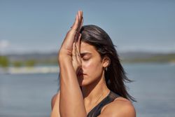 Close up of young woman with her eyes closed holding her hands in yoga pose