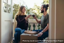 Couple sitting in their new home eating pizza and drinking wine 5rlMlb