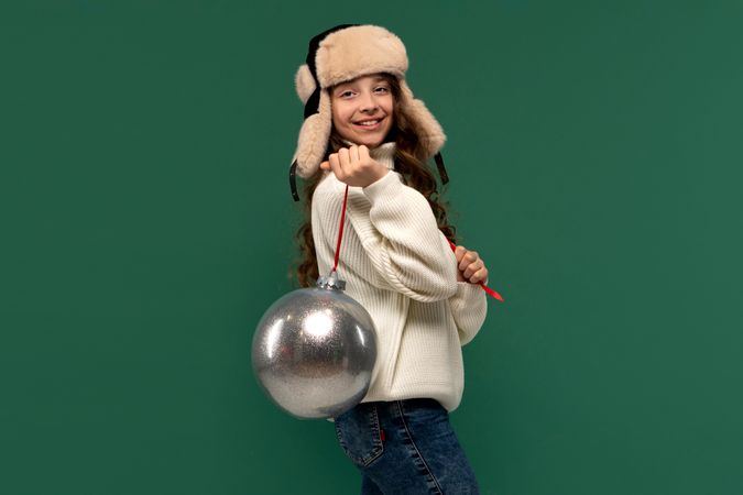 Cheerful girl posing with large silver ornament on ribbon