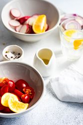 Ingredients of radishes, lemon and cherry tomatoes concrete background