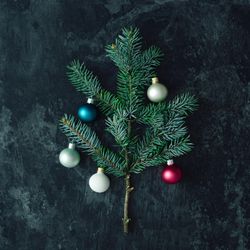 Christmas tree made of fir branches with baubles on marble table