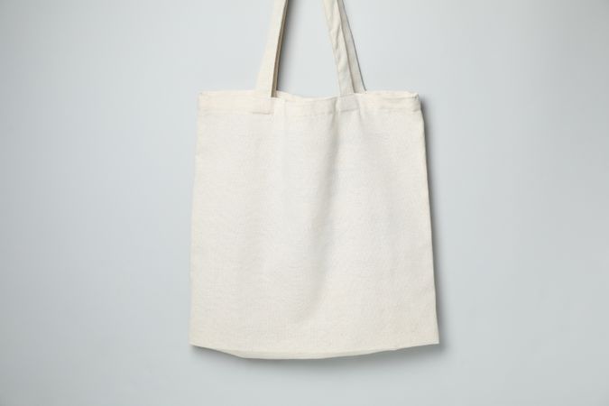 Empty light canvas bags on gray background, space for text.
