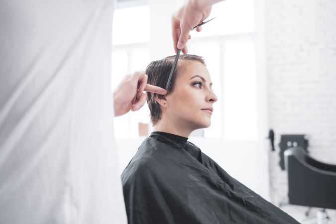 Hairdresser cuts woman's hair with scissors