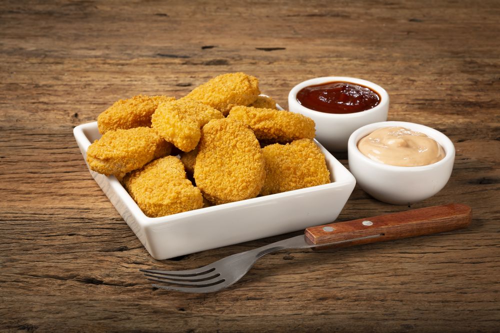 Fried chicken nuggets with ketchp and rose sauce.