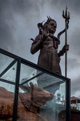 Statue of Shiva on cloudy day with cow underneath
