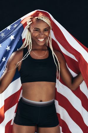 Happy woman athlete holding the US flag behind her