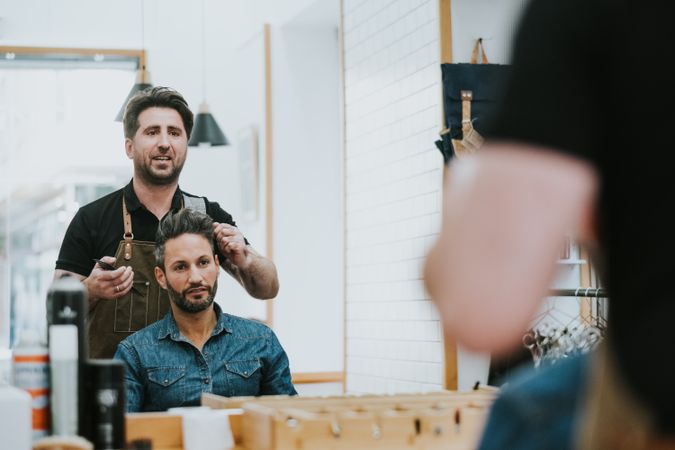 Barber combing hair to man in salon