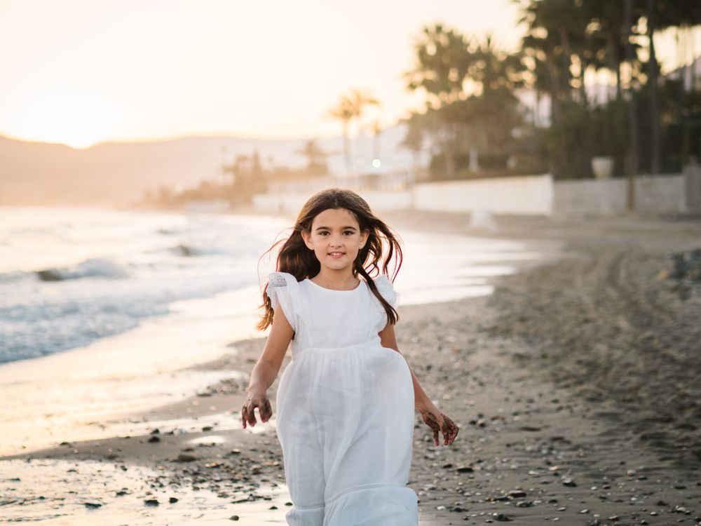 Excited girl running along beach in daylight