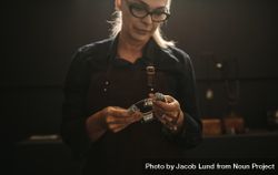 Older woman jeweler with professional ring finger measurer in workshop 439NO0