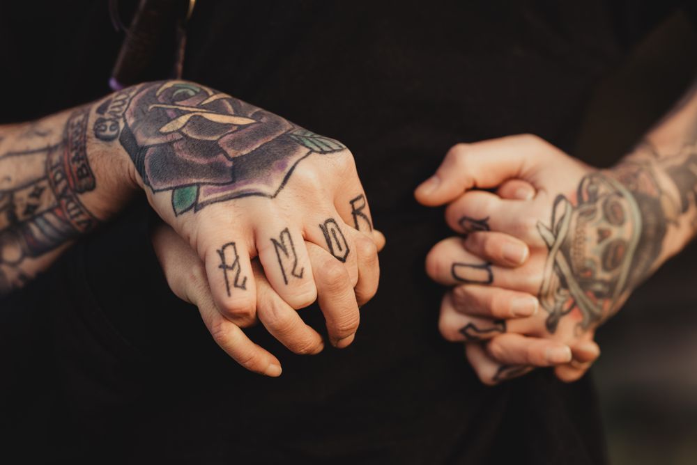 Man in tattoos holding hands of woman
