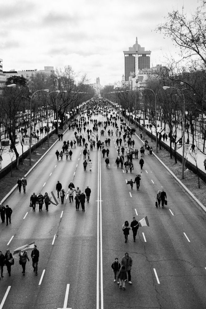 Group of people walking down main street in Madrid with flags
