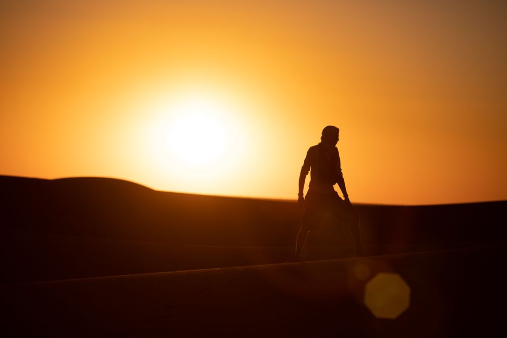 Anonymous traveler in desert during sunset