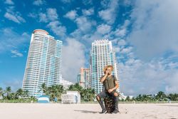 Male tourist sitting on his carrying suitcase at the beach. He is looking for directions Horizontal view.