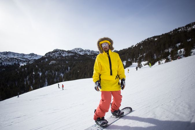Man in yellow parka and goggles with snowboard