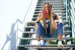 Laughing female skater checking phone on stairs, copy space 5XyZK4