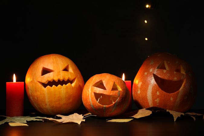 Halloween pumpkins and candles on dark background, copy space