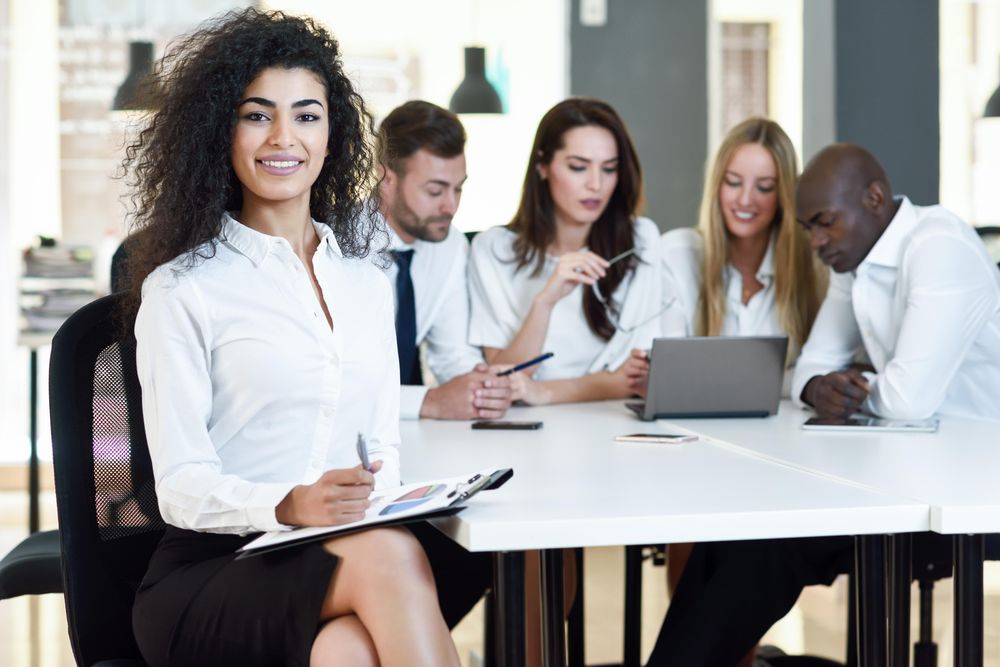 Curly haired businesswoman smiling in office looking at camera