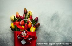 Tulips in shopping bag with gift, red ribbon and heart ornaments on grey background with copy space 0gXXAj