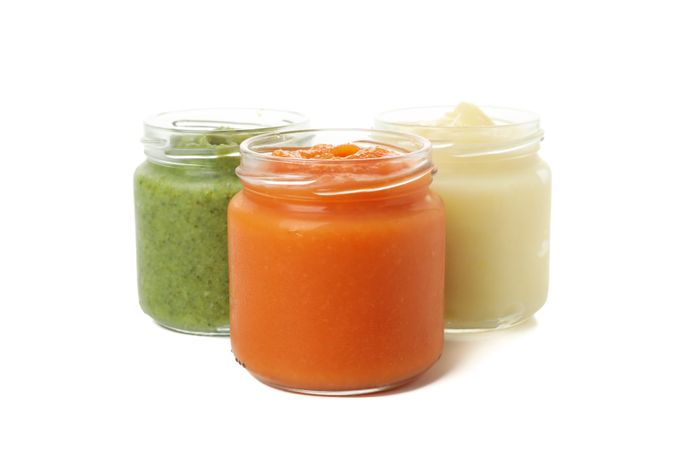 Glass jars with healthy baby food isolated on plain background
