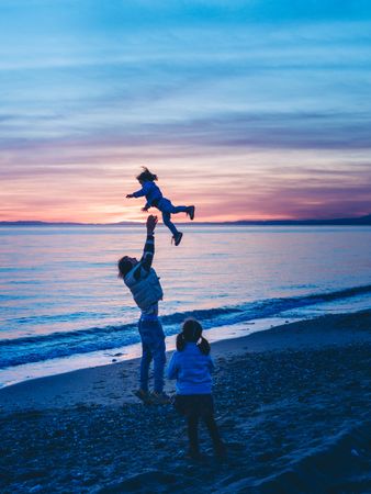 dad rocking kid at the beach