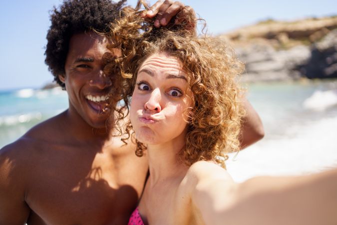 Man and woman taking funny selfie with sea in the background