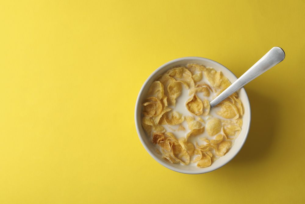 Bowl with muesli and milk on yellow background