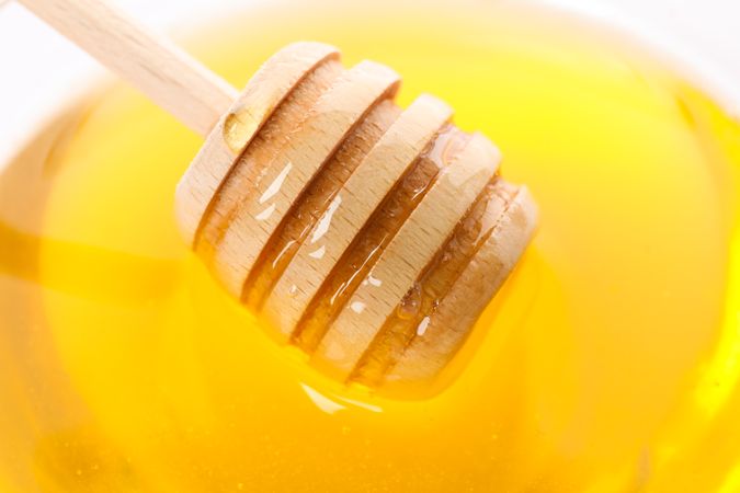 Dipper in honey on whole background, close up
