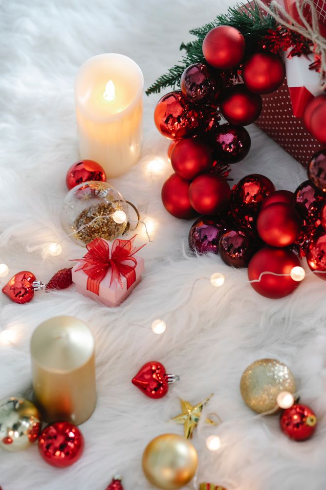 Red and gold Christmas baubles and candles on furry textile