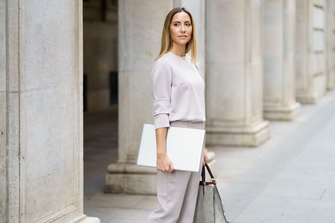 Confident businesswoman with laptop on street