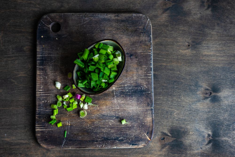 Freshly cut green onions on wooden board