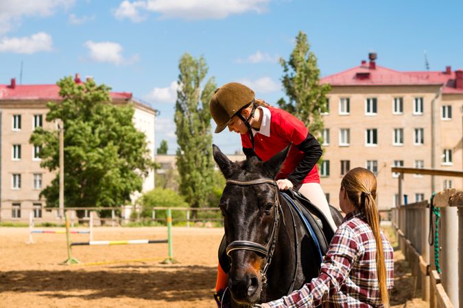 Young rider adjusts on horse with instructor's help