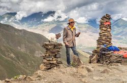 Tibet - August, 29 2014: Man near stacks of stones in mountains