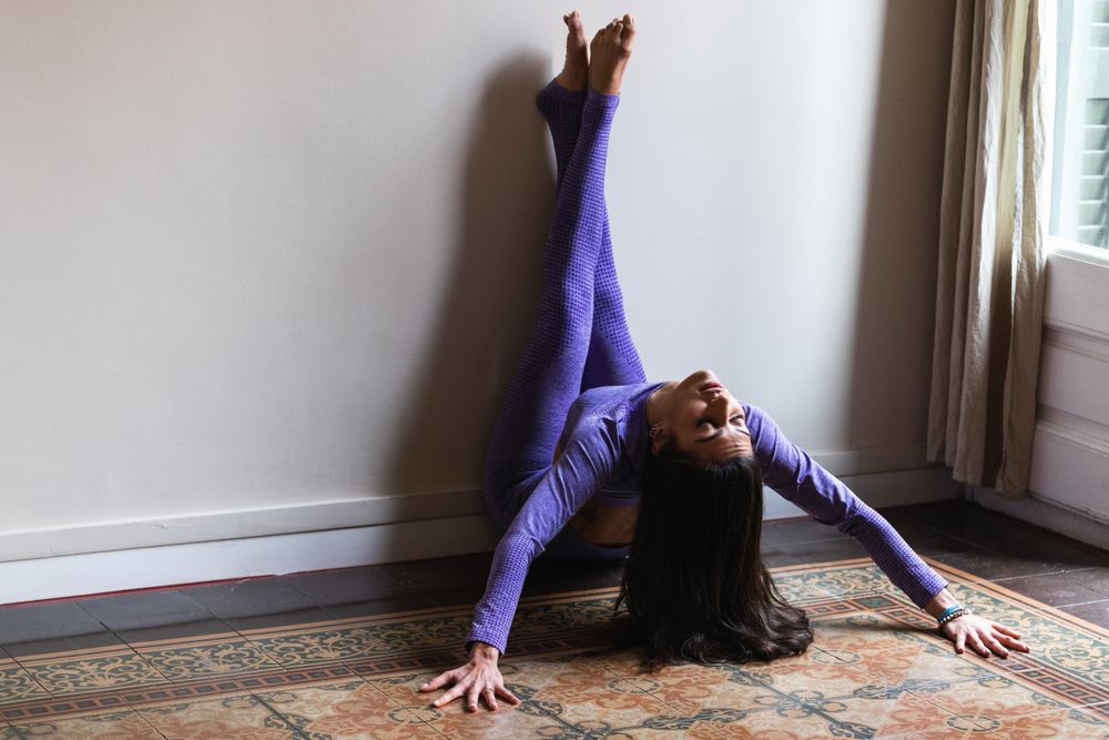Peaceful young woman with closed eyes practicing yoga at home