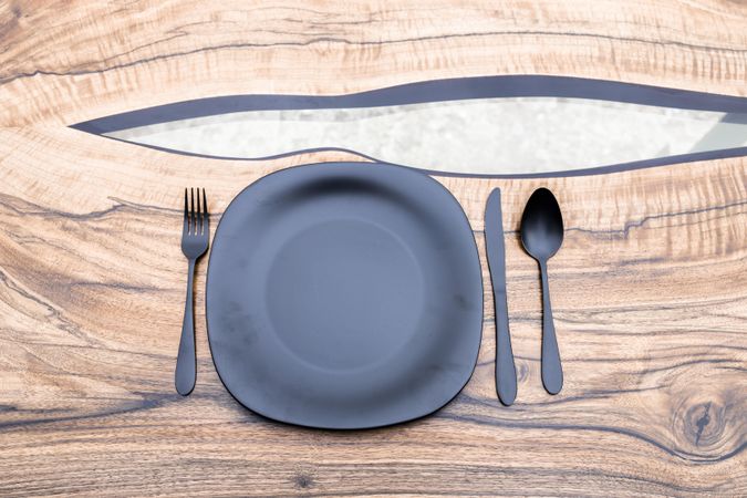Cutlery set with dark matching plate on stylish wooden table