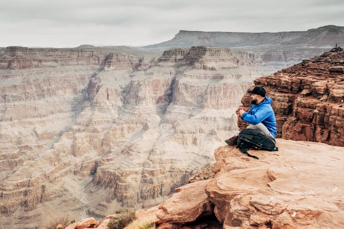Male having rest on edge of rock and relishing beverage