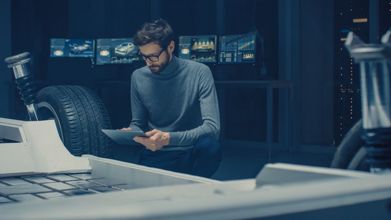 Automobile Design Engineer Sitting Beside Hybrid Electric Car Chassis Platform Prototype