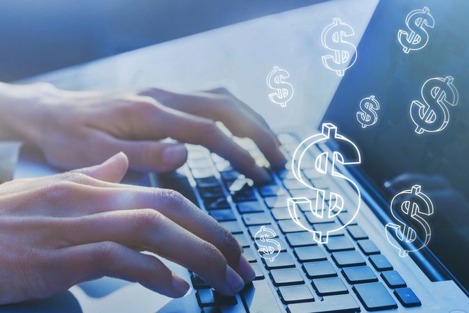 Hands Typing on Laptop with Floating Dollar Sign Symbols
