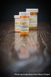 Variety of Non-Proprietary Prescription Medicine Bottles on Reflective Wooden Surface. 5oDkAG