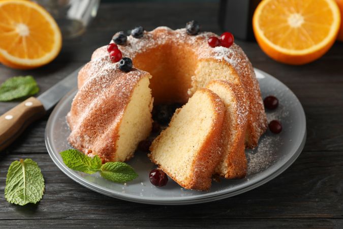 Cake with powdered sugar, berries and mint on wooden background, close up