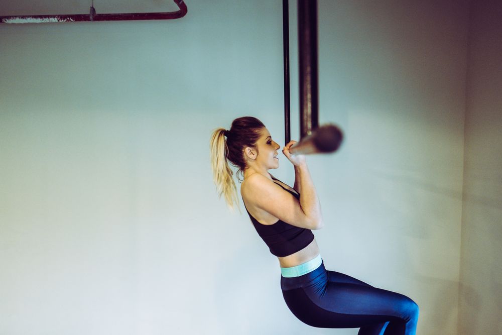 Young woman doing pull ups in gym
