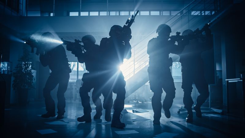 Masked Fireteam of Armed SWAT Police Officers Storm a Dark Seized Office Building with Desks and Computers.